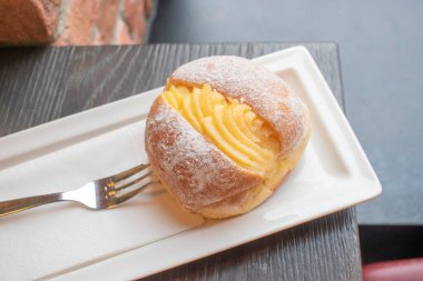 Portekiz çöreği ya da beyaz tabakta yumurta kremalı Berliner. Krema ve şekerle dolu kızarmış bir tatlı hamurdan oluşuyor. Seçici odak