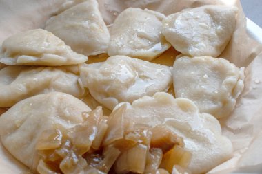 Otantik cilacı pierogi, bu geleneksel yemeğin lezzetli ve rahatlatıcı özelliklerini sergileyerek, bir tabakta karamelize edilmiş soğan eşliğinde mükemmelliğe ulaşır..
