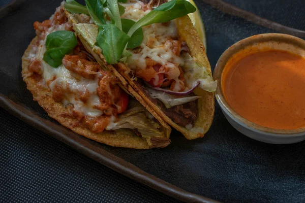 Flavorful Mexican-style tacos featuring succulent shrimp, tomatoes, cheese, chili, and onions, served with a side of hot and tangy Mexican sauce for a spicy and satisfying bite.