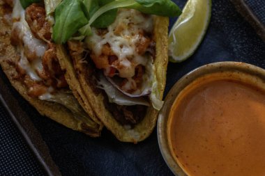 Lezzetli karides, domates, peynir, acı biber ve soğan içeren Meksika usulü takolar baharatlı ve tatminkar bir lokma için Meksika sosu ile servis edilir..