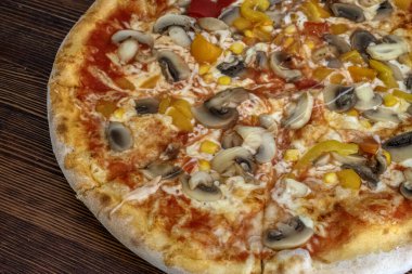 Funghi pizza: Domates soslu, erimiş peynirli, aromalı mantarlı, canlı biberli ve tatlı mısırlı ağız sulandıran bir pizza, hepsi de ahşap bir masada servis ediliyor. Tatmin edici ve sağlıklı bir yemek deneyimi için mükemmel bir lezzet kombinasyonu..