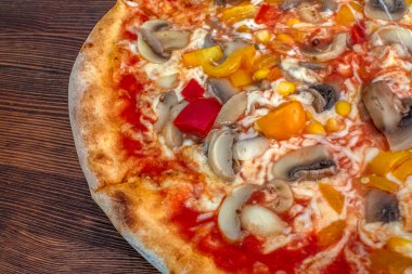 Funghi pizza: Domates soslu, erimiş peynirli, aromalı mantarlı, canlı biberli ve tatlı mısırlı ağız sulandıran bir pizza, hepsi de ahşap bir masada servis ediliyor. Tatmin edici ve sağlıklı bir yemek deneyimi için mükemmel bir lezzet kombinasyonu..