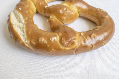 Freshly baked soft pretzel with a sprinkle of salt, offering a delightful combination of softness and savory flavor. Presented on a white background for a homemade feel.