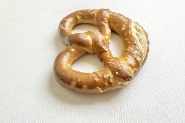 Freshly baked soft pretzel with a sprinkle of salt, offering a delightful combination of softness and savory flavor. Presented on a white background for a homemade feel.