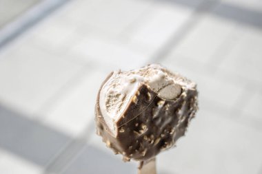 Çikolatalı, fındıklı, klasik sütlü çikolatalı dondurma. Arkaplan olarak halka açık bulanık bir yer olan stok fotoğrafları