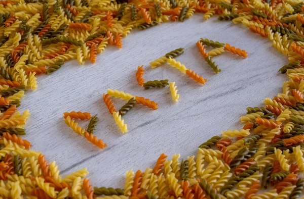 Makarna kelimesi makarna çerçevesinde beyaz ahşap bir arka planda fusilli makarnadan türetilmiştir. Yüksek kalite fotoğraf