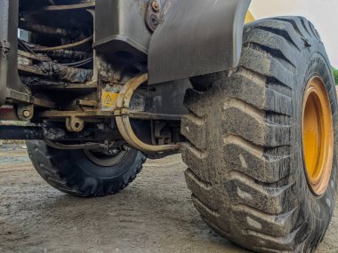 Kirli bir yük tekerine yakın çekim, büyük bir lastik izi, sarı ağır kazıcı kazıcısının lastik izleri, karanlık bir toprak üzerindeki kazıcı.