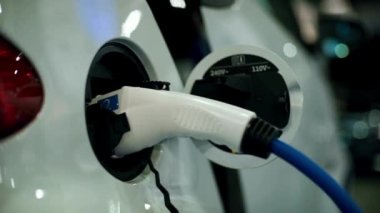 Bir arabayı şarj istasyonunda şarj etmek. Modern şarj aleti elektrikli bir arabaya takılı. Yenilikçi elektrikli hibrit araba şarj ediliyor