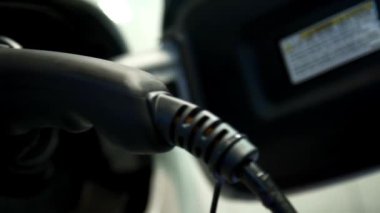 Elektrikli araba şarj oluyor. Şarj istasyonunda modern elektrikli araba şarj ediliyor. Elektrik hortumu bir elektroarabaya yerleştiriliyor.