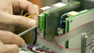 Teknoloji fabrikası işçileri seçilen yedek parçalardan elektronik ürünler monte ediyorlar. Elektronik fabrikasının arka planında devre tahtaları var.