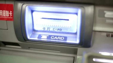 Bankamatik kasasına para çeken bir kredi kartı yerleştirirken yakın plan görüntüsü.