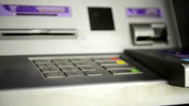 ATM 'den para çekmek için kredi kartı kullanan, PIN kodunu giren alışveriş yapan bir adam.