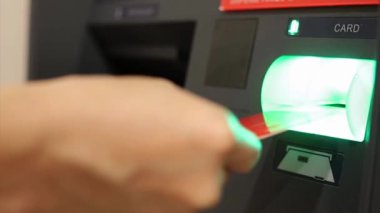 ATM 'de para çekmek için kredi kartı kullanan bir adam. Şifre takıyor, alışveriş merkezinden para alıyor.
