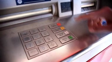 ATM 'de para çekmek için kredi kartı kullanan bir adam. Şifre takıyor, alışveriş merkezinden para alıyor.