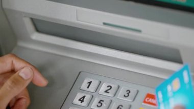 ATM 'nin önünde kredi kartıyla nakit para tutan kişi.