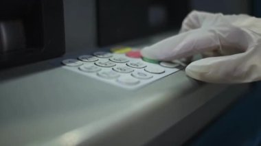 ATM adam eli pin numarasını girerken kapatıyor. Düğmelere basmak, pin anahtarı bankasına girmek.