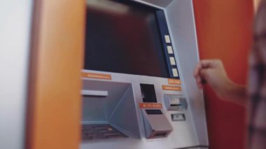 ATM 'den para çekmek için kredi kartı kullanan, PIN kodunu giren alışveriş yapan bir adam.