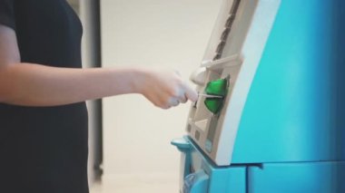 ATM 'den para çekmek için kredi kartı kullanan, PIN kodunu giren alışveriş yapan bir adam.