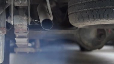 Arka planda bulanık hava kirliliği olan bir arabanın egzoz borusundan çıkan dumanın odak noktası