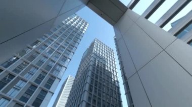 Gökdelen Şehri mavi gökyüzü alçak açılı kamera şehir merkezindeki ofis binalarının hareketlerini gösteriyor.