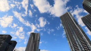 Gökdelen Şehri mavi gökyüzü alçak açılı kamera şehir merkezindeki ofis binalarının hareketlerini gösteriyor.