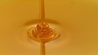 Sarı arka planda izole edilmiş bal akışı. Koyu arkaplandan damlayan sıvı bal, akan şurup. Sağlıklı gıda diyeti HD
