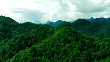 4K antenli, güzel yeşil bir ormanın üzerinde, kırsal bir arazide, doğu tropikal ormanlarında uçan bir dağ tepesi. Drone görünümlü hızlı çekim