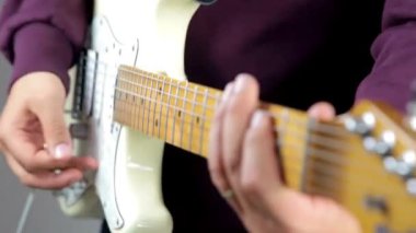 Gitarist eli elektro gitar teline tıngırdıyor. Levrek elleri yakın çekim izole edilmiş.