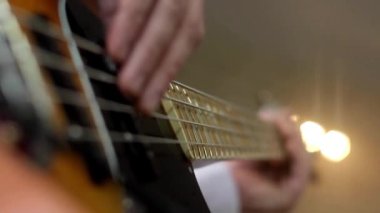 Yakından gelen adam gitar çalıyor. Tanınmaz halde. Bas gitar çalıyor.