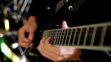 Yakından gelen adam gitar çalıyor. Tanınmaz halde. Bas gitar çalıyor.