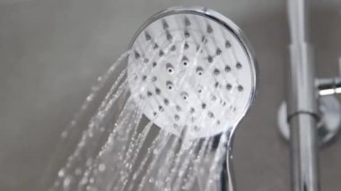 Gümüş krom duş başlığı su sıçratıyor. Banyo modern banyodan akıyor.