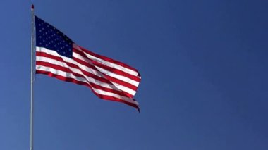 Rüzgarda dalgalanan Amerikan Bayrağı mavi bir arka planda. Amerikan Bayrağı. Mavi gökyüzünün önünde Amerika Birleşik Devletleri 'nin ünlü bayrağını sallıyordu. Bağımsızlık Günü