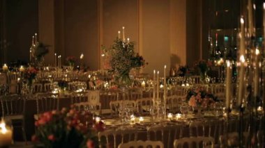 Şatafatlı düğün iç mimarisi çiçeklerle süslenmiş masa dekorasyonu iç mekan masa dekorasyonu şampanya flüt mumlarıyla detaylar ayarlanıyor.