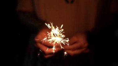 Elinde parlak bir maytap tutan kişi Noel ve yeni yılı kutluyor.