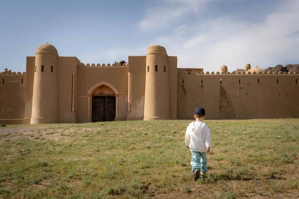 Eski kalenin arka planında sırt çantası olan beyaz elbiseli genç bir kadın.