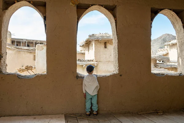 Eski duvarın arkasında sırt çantası olan mavi elbiseli genç bir kadın.