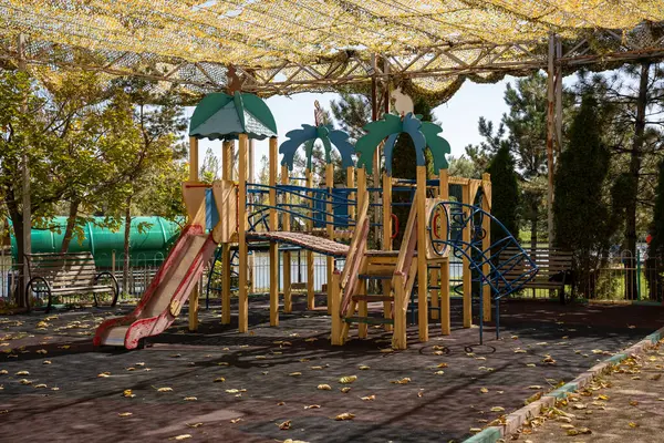 Sonbahar parkında sarı şemsiyeli boş oyun alanı