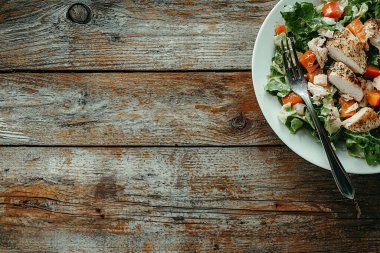 Tahta arka planda tavuk, domates ve roka ile sağlıklı bir salata. Üst Manzara. kopyalama alanı. seçici odak