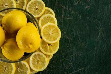 Dilimlenmiş limonlar yeşil boyalı kırsal bir masa üzerinde dairesel bir düzende dizilmiş.