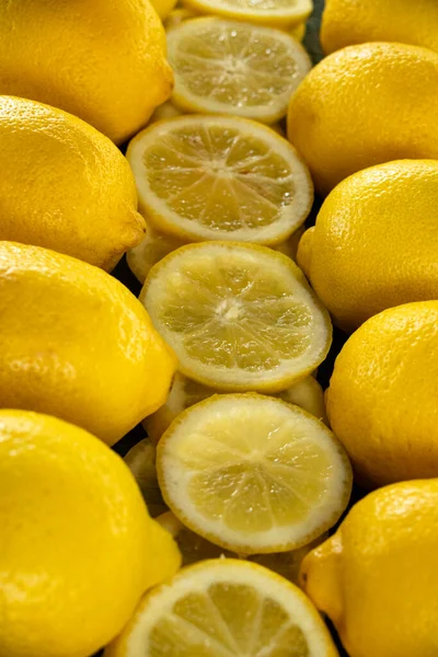 Bir sıra bütün ve dilimlenmiş limon parlak sarı bir zemin oluşturuyor.
