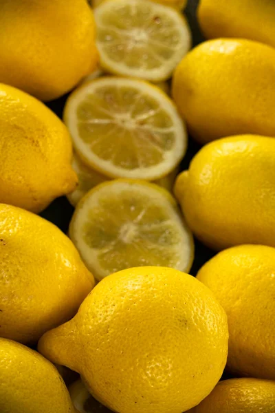 Bir sıra bütün ve dilimlenmiş limon parlak sarı bir zemin oluşturuyor.