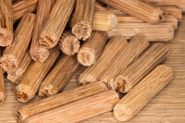 Meşe ağacının arka planında meşe çengelli iğne yığını, iki parça ahşap, eklem ve doğramacıyı birleştirmek için çengelli iğne.