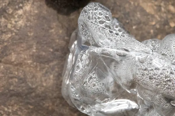 Kayalarda duran plastik bir su şişesindeki buharlaşmayı kapat. Çöp, çöp çevre için kötüdür.. 