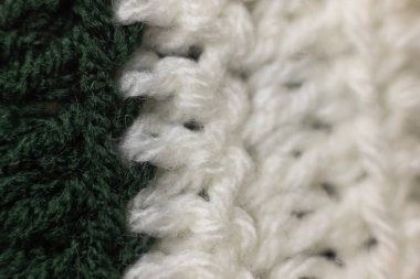 Avcı yeşil ve beyaz bir battaniyeye dikilmiş dikey örgü örgüleri büyükannemin evini hatırlatıyor, rahat ve sıcak bir arka plan.