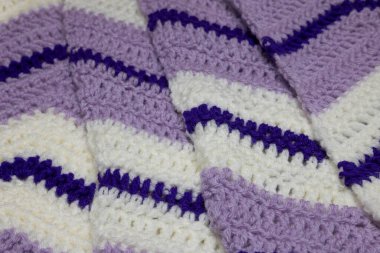 Katlanmış eflatun, mor, beyaz ve kraliyet mor zigzag battaniyesi beyaz ve avcı yeşil aksanlı, örülmüş veya örülmüş, size büyükannenin evini hatırlatıyor.