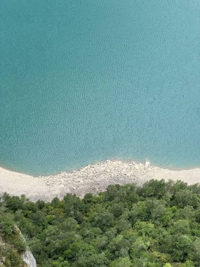 İspanyol Pireneleri 'nde dağ bitkileriyle birlikte turkuaz bir göl kıyısı manzarası.