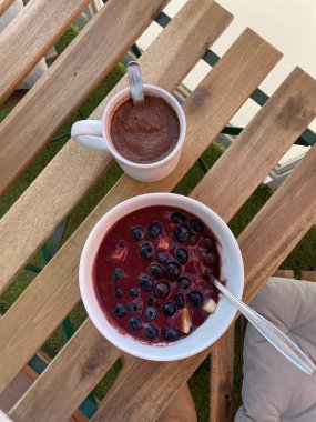 Kadının eli florit taşından bir kolye tutuyor. Arka planda gitar ve ukulele asılı.