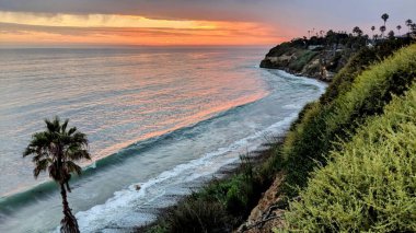 Günbatımları, sörfçüler, siluetler, gelgit havuzları, palmiye ağaçları ve okyanus kaya heykelleri ile Swamis Resif Sörf Parkı, Ay ışığı, Cardiff ve Beacons sahillerinde daha fazlası Encinitas California 'da.