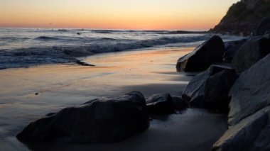 Swamis Sahili 'nde fırtınalı bir gün batımı. Encinitas California 'daki Swamis Resif Sörf Parkı' ndaki güzel sahil günbatımları, okyanus dalgaları, sörfçüler, gel-git havuzları, palmiye ağaçları ve kaya soyutlamaları ile San Diego 'nun kuzeyindeki tenha sahiller..