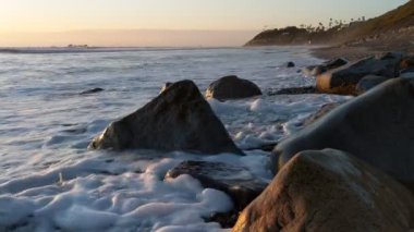 Swamis Sahili 'nin soğuk erimiş kayaları. 50 yıl önce, Swamis Resif Sörf Parkı Encinitas California 'daki dalgalı sörf karışımında eski iç nehir kayalarıyla çevrili kıyı şeridi boyunca uzanan erozyon kontrol kayaları..